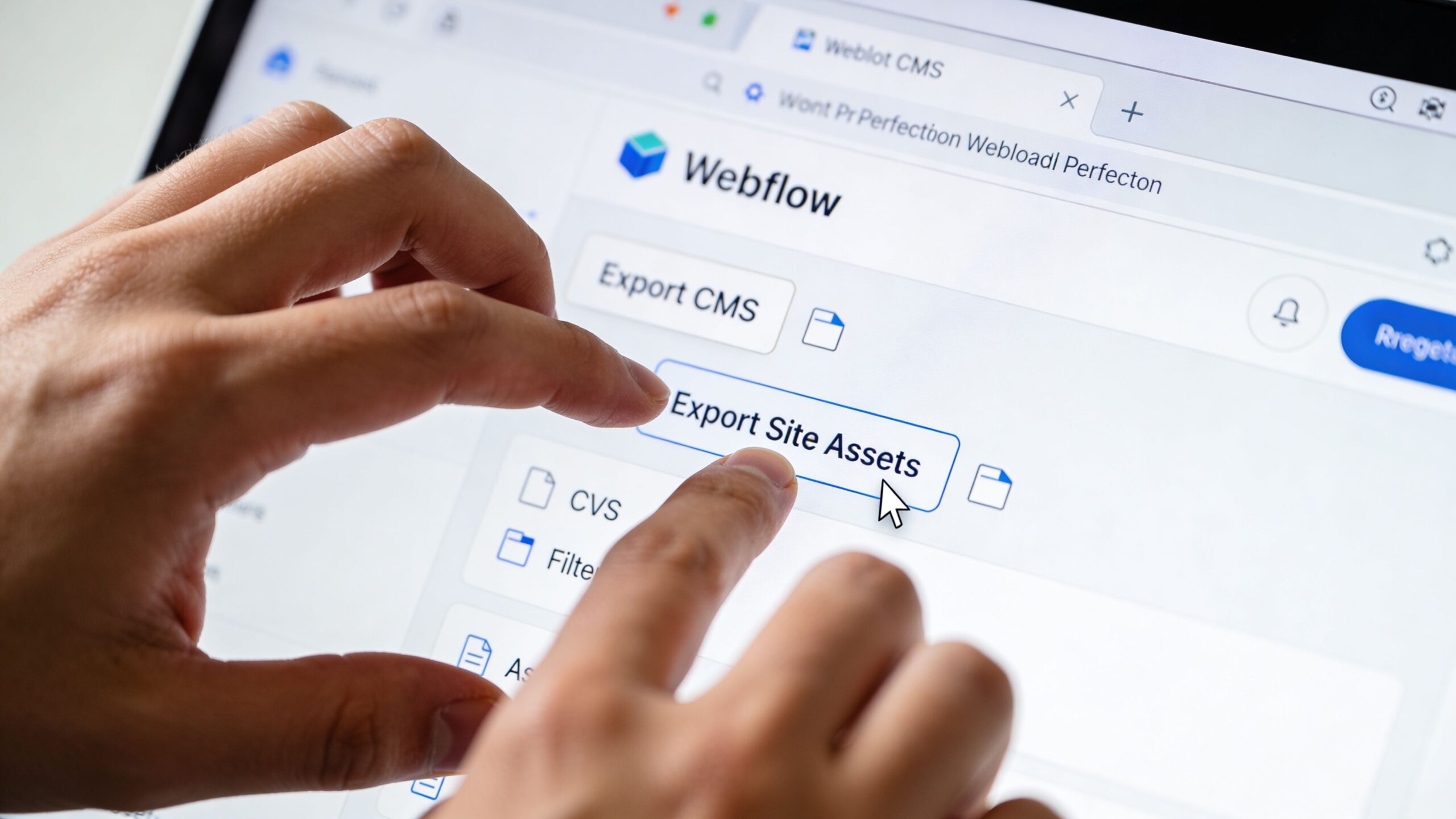 A close-up view of a person using a laptop to click the Export Site Assets button in Webflow.